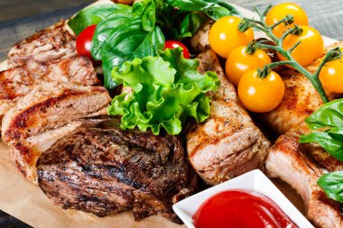 Çeşitli lezzetli ızgara et ve sebze taze salata ve kesme tahtası üzerinde ahşap arka plan Barbekü sosu ile kapatın. Sıcak et yemekleri büyük kümesi. Üstten görünüm