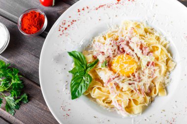 Fettuccine makarna et, jambon, yumurta, parmesan peyniri, fesleğen ve koyu ahşap arka plan, İtalyan mutfağı plaka üzerinde krema sos ile. Maddeler tablosundaki. Üstten görünüm