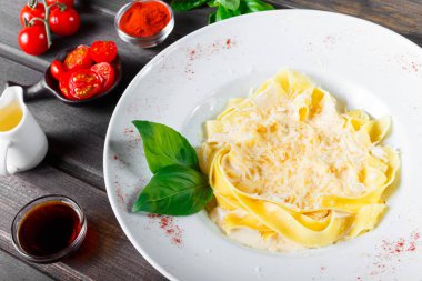 Fettuccine makarna parmesan peynir, fesleğen ve koyu ahşap zemin, İtalyan mutfağı üzerine krema sos ile. Maddeler tablosundaki.