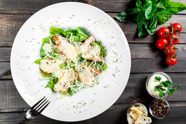 Tavuk göğsü, parmesan peyniri, kruton, karışık yeşillik, ahşap arka plan üzerinde marul salatası. Sağlıklı gıda. Maddeler tablosundaki