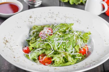 Karışık yeşillik, domates, ahşap zemin üzerine parmesan peyniri ile taze salata. Sağlıklı gıda. Maddeler tablosundaki.