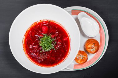 Ukrayna ve Rus geleneksel pancar çorbası - pancar çorbası plaka, ekşi krema ve sarımsak ve koyu ahşap arka plan üzerinde otlar ile buns. Ev yapımı yiyecek.