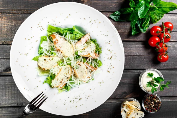 Tavuk göğsü, parmesan peyniri, kruton, karışık yeşillik, ahşap arka plan üzerinde marul salatası. Sağlıklı gıda. Maddeler tablosundaki