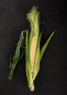 Karanlık bir taş tablo üzerinde taze mısır. Gıda kavramı, üstten görünüm.
