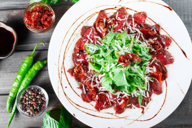 Roka, kurutulmuş domates ve peynir ile Dana carpaccio koyu ahşap zemin üzerine parmesan. Lezzetli meze. Üstten görünüm.