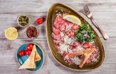 Hafif ahşap zemin üzerine roket salata, Parmesan peyniri, domates et Carpaccio. Aperatifler ve şarap meze ayarlayın. Maddeler tablosundaki. Üstten görünüm