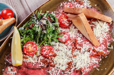 Hafif ahşap zemin üzerine roket salata, Parmesan peyniri, domates et Carpaccio. Aperatifler ve şarap meze ayarlayın. Maddeler tablosundaki. Üstten görünüm