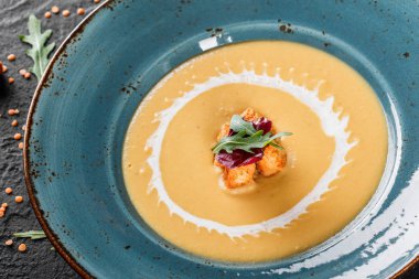 Krem plaka üzerinde ekmek kırıntıları ile mercimek çorbası. Üstten görünüm bir koyu gri taş yüzeye. Sağlıklı vegan gıda.