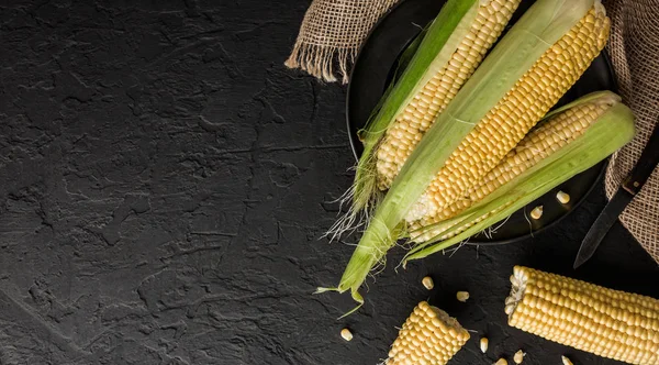 Taze mısır koçanı plaka üzerinde karanlık taş tablo üzerinde. Gıda kavramı. Alan üst görünüm Kopyala.