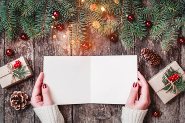 Noel hediyeleri, çam dalları ve şeker ile ahşap arka plan üzerinde Noel Baba'ya bir mektup okuma ve yazma el. Noel ve mutlu yeni yıl kartı. Düz yatıyordu, en iyi görünümü