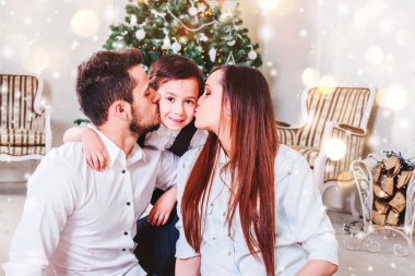 Noel aile gülümseyen ve öpüşme Xmas ağacı yakın. Noel ağacı ve mevcut hediye kutusu tarafından dekore edilmiş salon, ışık vermek rahat bir atmosfer. Yeni yıl tema. Tonlama