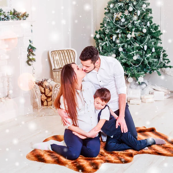 圣诞节家庭微笑和亲吻附近的圣诞树 客厅装饰着圣诞树和礼物盒 光线给舒适的气氛 新年主题 — 图库照片