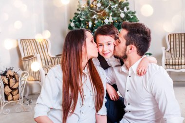 Noel aile gülümseyen ve öpüşme Xmas ağacı yakın. Noel ağacı ve mevcut hediye kutusu tarafından dekore edilmiş salon, ışık vermek rahat bir atmosfer. Yeni yıl tema. Tonlama