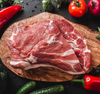 Çiğ et, sığır eti biftek yemek pişirmek için malzemelerle siyah arka plan üzerinde kesme tahtası üzerinde. Üstten görünüm