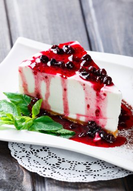 Çilek sosu ve plaka koyu arka plan üzerinde yeşil nane ile tatlı Cheesecake.