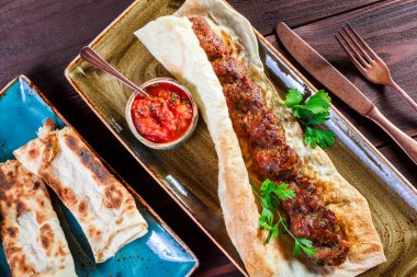 Sığır eti Kebap pide ekmek, domates sosu ve sebze ahşap arka plan üzerinde. Sıcak et yemekleri.