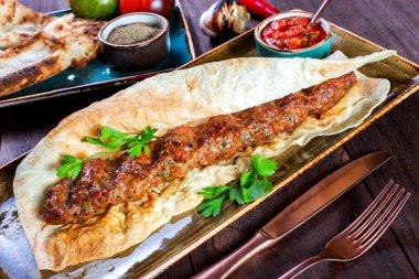 Sığır eti Kebap pide ekmek, domates sosu ve sebze ahşap arka plan üzerinde. Sıcak et yemekleri.