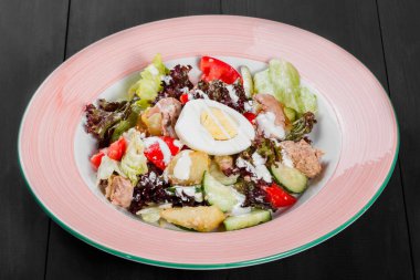 Ton balıklı salata marul, yumurta, salatalık, domates ve patates plaka üzerinde koyu ahşap arka plan ile. Akdeniz yemekleri. Üstten görünüm