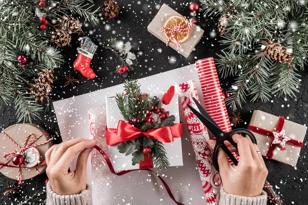 女性手パック休日背景のモミの枝 松ぼっくりが付いて赤いリボンとクリスマス ギフト ボックス クリスマスと幸せな新年カード ボケ味が光る フラット横たわっていた トップ ビュー — ストック写真