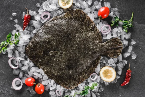 Pesce flounder intero crudo con spezie su ghiaccio su fondo di pietra scura. Layout creativo fatto di pesce, vista dall'alto — Foto Stock