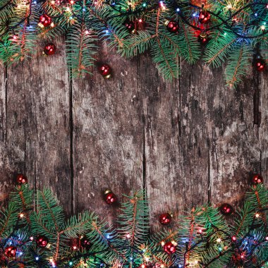 Noel çam dalları ile ışık ve ahşap arka plan üzerinde kırmızı süslemeleri. Noel ve mutlu yeni yıl kompozisyon. Düz yatıyordu, en iyi görünüm. Kopya alanı
