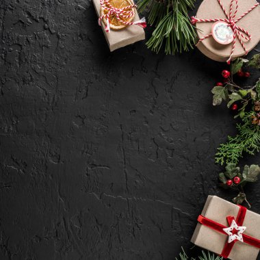 Noel ağacı dalları, hediyeler, çilek, çam kozalakları kar taneleri ile koyu arka plan üzerinde yaratıcı çerçeve yaptı. Noel ve yeni yıl tema. Düz yatıyordu, en iyi görünüm, metin için yer