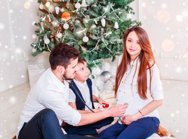 Noel aile gülümseyen ve öpüşme Xmas ağacı yakın. Noel ağacı ve mevcut hediye kutusu tarafından dekore edilmiş salon, ışık vermek rahat bir atmosfer. Yeni yıl tema. Tonlama