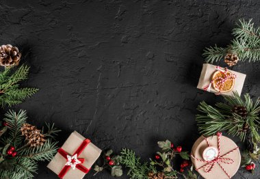 Yaratıcı düzen çerçeve yaptı Noel ağaç dalları, çam kozalakları, koyu arka plan üzerinde hediyeler. Noel ve yeni yıl tema., kar. Düz yatıyordu, en iyi görünüm, metin için yer