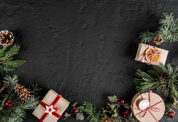 Yaratıcı düzen çerçeve yaptı Noel ağaç dalları, çam kozalakları, koyu arka plan üzerinde hediyeler. Noel ve yeni yıl tema., kar. Düz yatıyordu, en iyi görünüm, metin için yer
