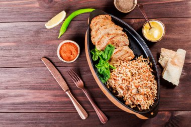 Pişmiş yemek sığır eti, şehriye, pirinç, mantar, soğan tereyağı, baharat ve konyak ahşap masa üzerinde tavada hizmet verdi. Sıcak et Gürcü mutfağı. Üstten görünüm