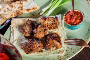 Domates sosu ve Yeşiller ile şarap bir tabakta servis ile sığır eti şiş ızgara. Sıcak et yemekleri. Üstten görünüm