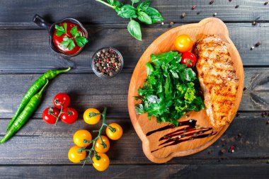 Izgara tavuk fileto Taze sebze salatası, domates ve ahşap kesme tahtası üzerinde sos ile. Sıcak et yemekleri. Üstten görünüm