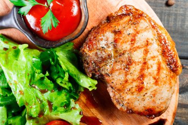 Izgara biftek domuz taze sebze salatası, domates ve ahşap kesme tahtası üzerinde sos ile. Sıcak et yemekleri. Üstten görünüm