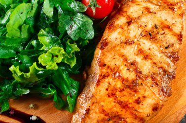 Izgara tavuk fileto Taze sebze salatası, domates ve ahşap kesme tahtası üzerinde sos ile. Sıcak et yemekleri. Üstten görünüm