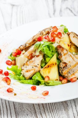 Tavuk göğsü, kavun, ananas, nar taneleri ile taze salata, marul yaprakları ve badem ahşap arka plan üzerinde plaka üzerinde yakın çekim. Üstten Görünüm