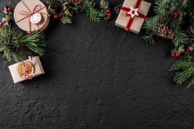 Yaratıcı düzen çerçeve yaptı Noel ağaç dalları, çam kozalakları, koyu arka plan üzerinde hediyeler. Noel ve yeni yıl tema, kar. Düz yatıyordu, en iyi görünüm, geniş kompozisyon