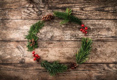 Noel çelenk çam dalları, koniler, kar taneleri ile ahşap arka plan üzerinde kırmızı dekorasyon. Noel ve mutlu yeni yıl tema. Düz yatıyordu, en iyi görünümü