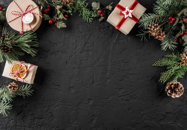 Yaratıcı düzen çerçeve yaptı Noel ağaç dalları, çam kozalakları, koyu arka plan üzerinde hediyeler. Noel ve yeni yıl tema, kar. Düz yatıyordu, en iyi görünüm, geniş kompozisyon