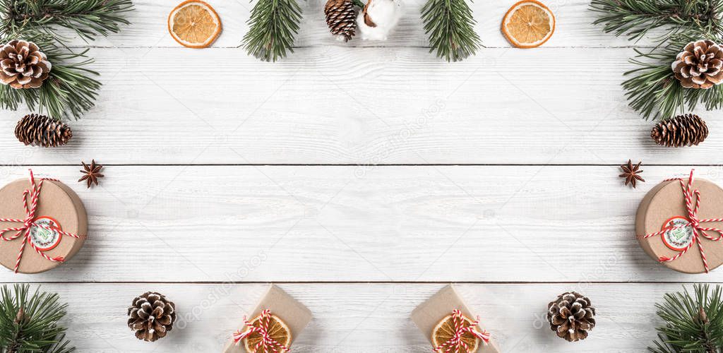 Christmas gift boxes on white wooden background with Fir branches, pine cones. Xmas and Happy New Year theme. Flat lay, top view, wide composition