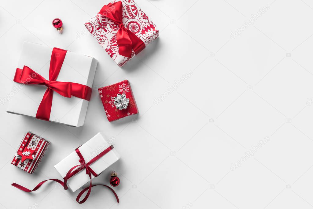 Christmas gift boxes with red ribbon and decoration on white background. Xmas and Happy New Year theme, snow. Flat lay, top view, wide composition