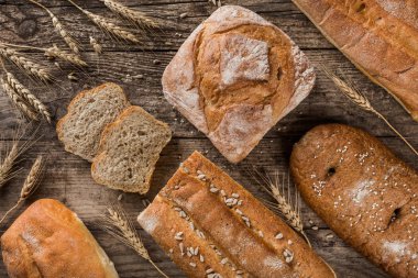 Farklı taze ekmek ve buğday rustik ahşap zemin üzerine spikelets. Yaratıcı düzen ekmek yaptım. Sağlıklı gıda kavramı, üstten görünüm, düz yatıyordu, kopyalama alanı