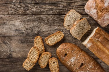 Farklı taze ekmek ve buğday rustik ahşap zemin üzerine spikelets. Yaratıcı düzen ekmek yaptım. Sağlıklı gıda kavramı, üstten görünüm, düz yatıyordu, kopyalama alanı