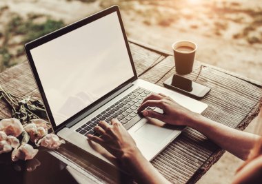 Kahve fincanı, çilek, şakayık çiçeği ve akıllı telefonlu kaba ahşap masada dizüstü bilgisayar kullanan ve daktilo kullanan genç bir kadın. Açık hava parkında çalışan serbest çalışan biri. Tonlama