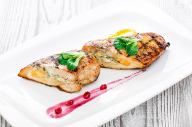 Ahşap arka plan üzerinde plaka üzerinde yumurta ve peynir ile doldurulmuş ızgara tavuk göğsü kapatın. Sıcak et yemekleri. Üstten görünüm