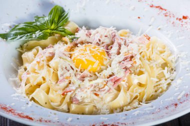 Fettuccine makarna et, jambon, yumurta, parmesan peyniri, fesleğen ve koyu ahşap arka plan, İtalyan mutfağı plaka üzerinde krema sos ile. Maddeler tablosundaki