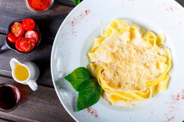 Fettuccine makarna parmesan peynir, fesleğen ve koyu ahşap zemin, İtalyan mutfağı üzerine krema sos ile. Maddeler tablosundaki