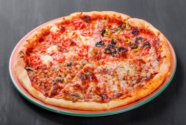 Karışık pizza tavuk, domates, mantar, jambon, salam, zeytin ve koyu ahşap zemin üzerine peynir ile İtalyan yemeği. Ev yapımı pizza. 