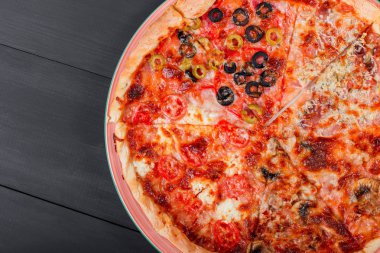 Karışık pizza tavuk, domates, mantar, jambon, salam, zeytin ve koyu ahşap zemin üzerine peynir ile İtalyan yemeği. Ev yapımı pizza. Üstten Görünüm