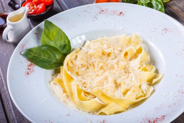 Fettuccine makarna parmesan peynir, fesleğen ve koyu ahşap zemin, İtalyan mutfağı üzerine krema sos ile. Maddeler tablosundaki
