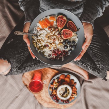 Yün kazak ve vegan pilav Hindistan cevizi lapası incir, çilek, fındık yemek kot kadında. Sağlıklı kahvaltı malzemeler. Yeme, vegan gıda kavramı temiz